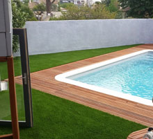 piscine entourée de bois et de pelouse